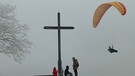 Ein Paraglider am Gipfelkreuz des Bergs Rodenstein in der Fränkischen Schweiz. | Bild: Norbert Haselbauer, Kirchehrenbach, 16.01.2024