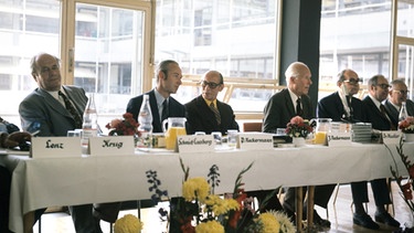 Der Unternehmer und Firmenchef Dr. Josef Neckermann (3.v.l) und sein Sohn Peter Neckermann (2.v.l.) sitzen während der Hauptversammlung der Neckermann AG 1973 am Vorstandstisch. | Bild: picture-alliance/dpa