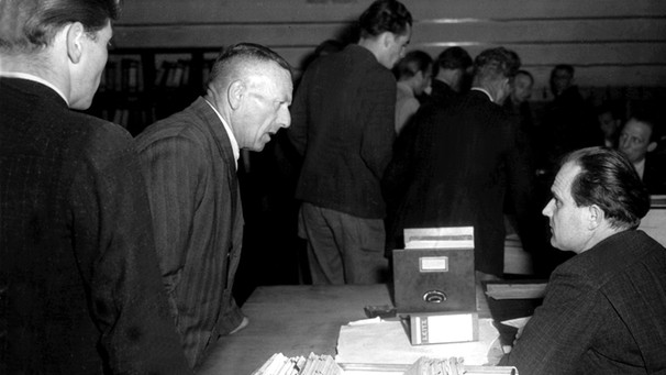 Männliche Arbeitssuchende erkundigen sich in den 50er Jahren in der Vermittlungsstelle eines Arbeitsamtes nach freien Stellen. | Bild: picture-alliance/dpa
