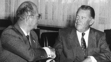Mit einem Handschlag zwischen dem Philips-Konzernchef Wisse Decker (l) und Max Grundig (M) wurde nach der Unterzeichnung der Verträge am 07.02.1984 in Fürth die Übernahme besiegelt.  | Bild: picture-alliance/dpa