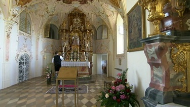 Mann entzündet Kerzen auf Altar | Bild: Bayerischer Rundfunk