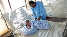 Ein Arzt untersucht ein Kind, das mit Cholera infinziert ist.  | Bild: picture alliance/Xinhua