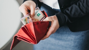 Eine Frau die Geld in ihren Geldbeutel steckt. | Bild: BR/Julia Müller