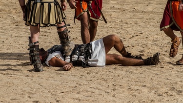 Ein Schaukampf von Gladiatoren in einer Arena. Ein Mann liegt am Boden. | Bild: colourbox.com