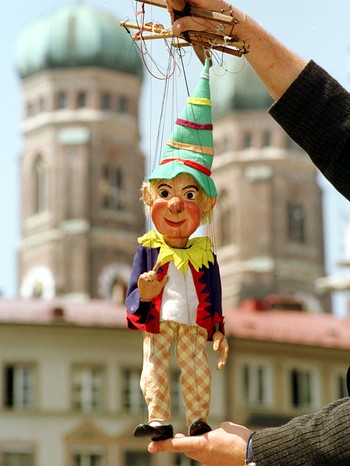 Vor den Türmen der Münchner Frauenkirche winkt der Kasperl der Augsburger Puppenkiste. | Bild: picture-alliance/dpa