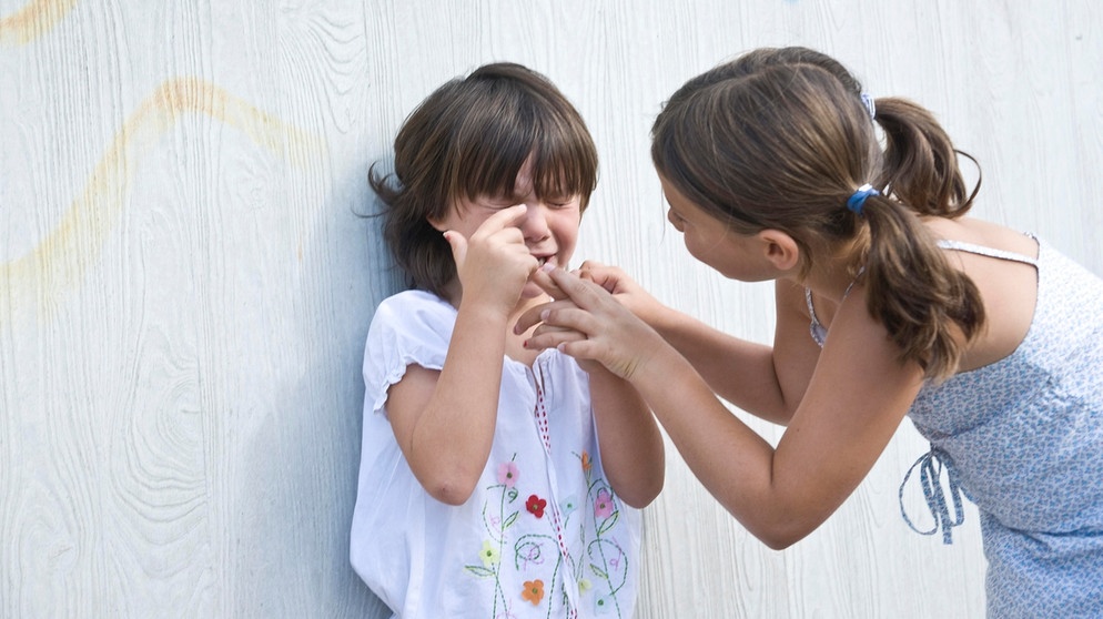 Ein größeres Mädchen versucht ein weinendes kleineres Mädchen zu trösten. | Bild: picture alliance / imageBROKER | uwe umstätter