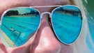 Ein Schwimmbecken spiegelt sich am 21.06.2017 in einem Freibad in Hannover (Niedersachsen) in der Sonnenbrille einer Frau.  | Bild: dpa-Bildfunk/Silas Stein