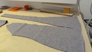 Die fertig zugeschnittenen Teile für den grauen Mantel liegen auf einem Tisch. | Bild: BR | Kathrin Reikowski