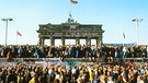 Menschenmenge am 10. November 1989, dem Tag des Mauerfalls, vor und auf der Berliner Mauer vor dem Brandenburger Tor.  | Bild: picture-alliance/dpa