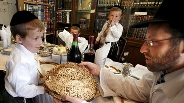 Eine ultraorthodoxe jüdische Familie feiert in der Siedlung Betar Illit im Westjordanland Seder, das Pessach-Abendessen (Aufnahme vom 2. April 2007). Das ungesäuerte Brot Mazza wird herumgereicht.  | Bild: picture alliance / dpa | epa Nati Shohat-Flash90