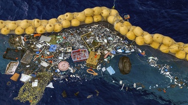Dieses Foto hat "The Ocean Cleanup" als Beweis seines Erfolgs veröffentlicht. Es zeigt schwimme Plastikstücke vor einer Dichtung im Meer.  | Bild: dpa-Bildfunk/The Ocean Cleanup