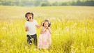 Zwei Kinder stehen mit großen Kopfhörern in einer Sommerwiese. | Bild: colourbox.com