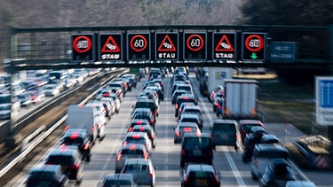 Dichter Verkehr schiebt sich über die Autobahn 8 in Fahrtrichtung Salzburg, während über der Straße auf einer digitalen Anzeige vor Stau gewarnt wird.  | Bild: dpa-Bildfunk/Matthias Balk
