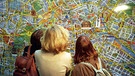 Menschen betrachten Stadtplan | Bild: picture-alliance/dpa