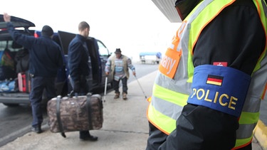 Polizisten begleiten abgelehnte Asylbewerber auf dem Flughafen Leipzig-Halle im sächsischen Schkeuditz.  | Bild: picture-alliance/dpa