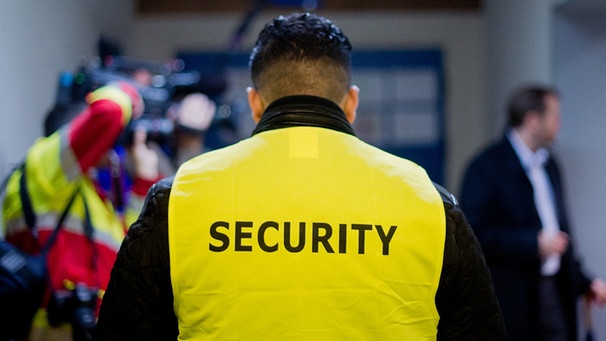 Ein Security-Mitarbeiter steht am 19.10.2015 in der Flüchtlingsunterkunft Mackensen Kaserne in Hildesheim (Niedersachsen).  | Bild: picture-alliance/dpa/Julian Stratenschulte
