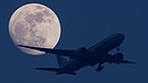 Ein Flugzeug bei Mondschein im Landeanflug. | Bild: pa/dpa/Daniel Reinhardt