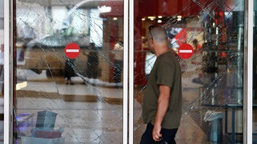 Ein Mann geht an zerborstenen Fenstern im Flughafen in Istanbul vorbei, wo es am 28. Juni zwei Explosionen gab | Bild: dpa-Bildfunk