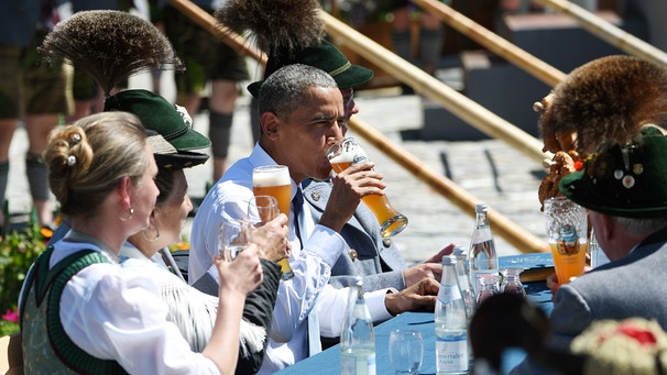US-Präsident Barack Obama (2.v.r.) sitzt am 07.06.2015 in Krün (Bayern) mit Einwohnern Krüns an einem Tisch auf dem Dorfplatz und trinkt aus einem Weißbierglas. | Bild: picture-alliance/dpa