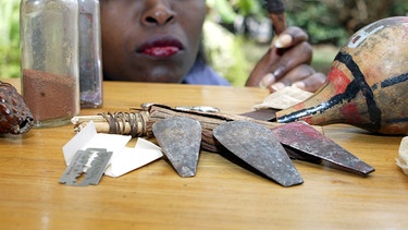 Missio-Mitarbeiterin Elisabeth schaut im kenianischen Ort Gilgil auf Instrumente, mit denen bis heute Mädchen beschnitten werden. | Bild: picture-alliance/dpa, Ursula Düren