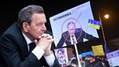 FOTOMONTAGE: Altkanzler Gerhard Schrüder und ein Protest-Plakat gegen Putins militärischen Angriff auf die Ukraine  | Bild: picture alliance / SvenSimon | Frank Hoermann/SVEN SIMON