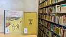 Ein jüdisches Buch und "Pünktchen und Anton", ein Werk von Erich Kästner, stehen in der Bibliothek. | Bild: Universität Augsburg