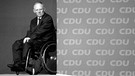 ARCHIVBILD: Wolfgang Schäuble (CDU) als Bundesfinanzminister wartet am 15.11.2010 beim CDU-Parteitag in Karlsruhe im Rollstuhl neben einer Wand mit CDU Schriftzügen.  | Bild: picture alliance / SvenSimon | Frank Hoermann/SVEN SIMON