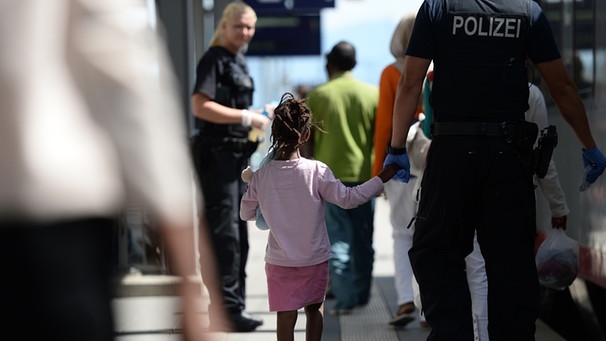 Ein Polizist führt am 04.08.2015 am Bahnhof in Rosenheim (Bayern) ein kleines Mädchen über den Bahnsteig. | Bild: picture-alliance/dpa/Andreas Gebert