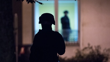 Polizist steht vor dem Fenster einer Wohnung in einem Wohngebiet in Chemnitz | Bild: picture-alliance/dpa