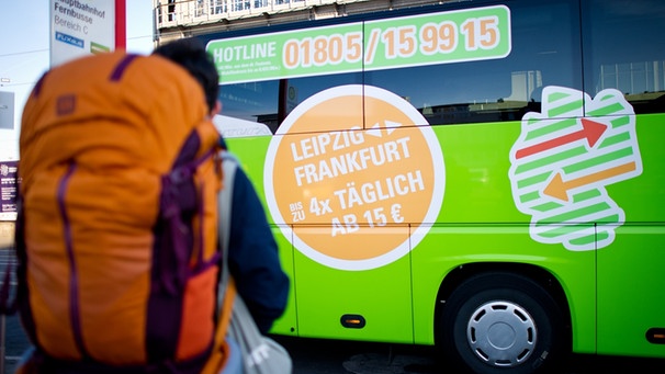 Flixbus steigt ins Grupenreise-Geschäft ein, ein Rucksacktourist steht vor einem Bus der Firmenflotte | Bild: picture-alliance/dpa/Christoph Schmidt
