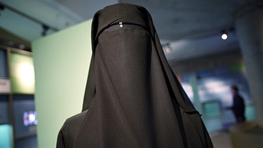 Eine Frau mit schwarzer Burka in einer Ausste | Bild: picture-alliance/dpa