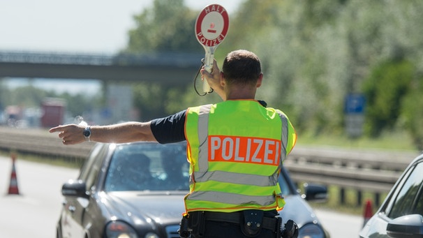 Ein Bundespolizist hält am 17.09.2015 an einer Kontrollstelle an der Autobahn A 3 kurz hinter der deutsch-österreichischen Grenze nahe Pocking (Bayern) ein Fahrzeug an. | Bild: dpa/Armin Weigel