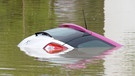 Nur noch die Heckklappe ist am 03.06.2013 in Rosenheim (Bayern) im Ortsteil Oberwöhr von einem Auto zu sehen, das von Überschwemmungen erfasst wurde. | Bild: picture-alliance/dpa