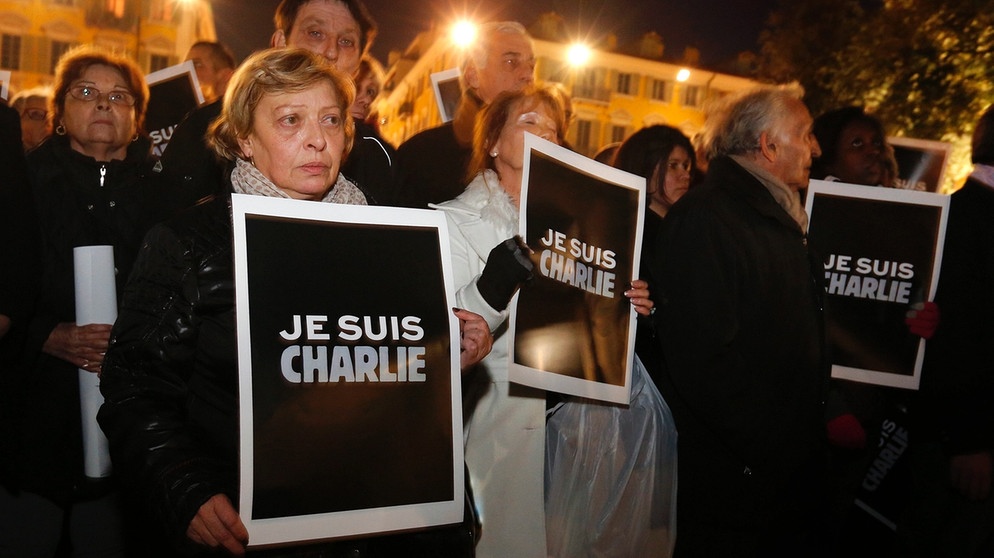  Menschen halten Plakate mit der Aufschrift "Je suis Charlie" (Ich bin Charlie) während einer Zusammenkunft in Nizza | Bild: dpa-Bildfunk