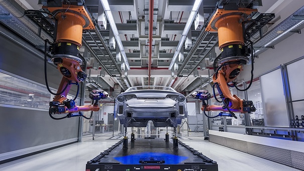 Zwei Roboter fahren auf Schienen an einem Audi entlang | Bild: picture-alliance/dpa