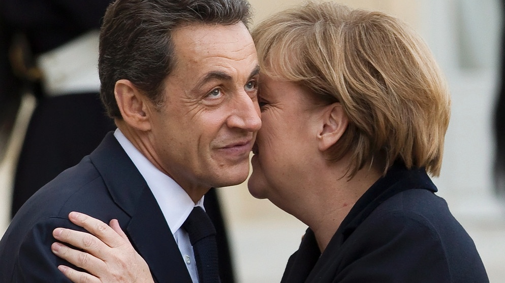 Sie werden nur noch Merkozy genannt: Kanzlerin Angela Merkel küsst Präsident Nicolas Sarkozy  | Bild: picture-alliance/dpa