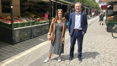 Wirtschaftsreferent Horst Müller und Citymanagerin Verena Tykvart stehen auf dem Fürther Wochenmarkt. | Bild: BR24/Michael Reiner
