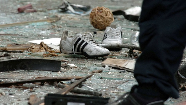 Schuhe liegen am 10.6.2004 zwischen den Scherben an der Explosionsstelle in Köln. Eine mit Nägeln gespickte Bombe war am Vortag in einem Friseurladen in einem Wohn- und Geschäftsviertel im Stadtteil Mülheim explodiert. | Bild: picture-alliance/dpa