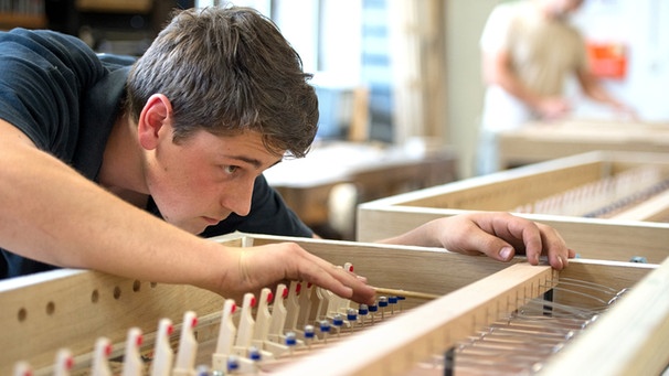 Symbolbild: Auszubildender montiert in einer Orgelbauwerkstatt eine Feder in eine Windlade.  | Bild: picture-alliance/dpa
