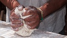 Symbolbild: Hände eines dunkelhäutigen Mannes, die Teig kneten | Bild: colourbox.com