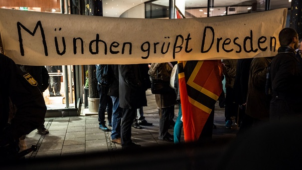 Sympathisanten der Pegida-Bewegung halten am 22.12.2014 in München ein Schild mit Aufschrift "München grüßt Dresden" in die Luft | Bild: picture-alliance/dpa