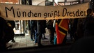 Sympathisanten der Pegida-Bewegung halten am 22.12.2014 in München ein Schild mit Aufschrift "München grüßt Dresden" in die Luft | Bild: picture-alliance/dpa
