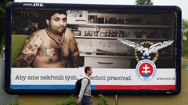 Ein Mann geht an einem Plakat der Partei "Slovenska narodna strana" (Slowakische Nationalpartei) auf dem unter einem Bild von einem tatowierten Mann, der einen Roma darstellen soll, geschrieben steht: "Wir ernähren nicht diejenigen, die nicht arbeiten". Bratislava, 5 Mai 2010 | Bild: picture-alliance/dpa