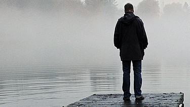 Ein Mann steht bei nebligem Wetter auf einem Steg  | Bild: picture-alliance/dpa