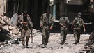 Rebellen-Kämpfer zwischen zerstörten Gebäuden in der Stadt Manbidsch in the city of Manbij/Manbidsch | Bild: Reuters/Rodi Said