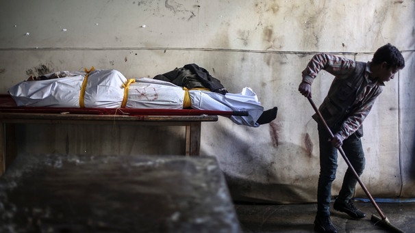 Syrischer Junge wischt den Boden - neben ihm liegt ein Toter | Bild: picture-alliance/dpa