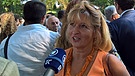 In einer Menschenmenge spricht eine blonde Frau mit BR-Reporter Clemens Verenkotte | Bild: BR/Attila Poth