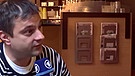 Zoltán Kiszelly sitzt mit BR-Reporter Clemens Verenkotte in einem Cafe und gestikuliert | Bild: BR/Attila Poth