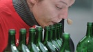 Mann bläst auf Bocksbeutel-Flaschen | Bild: picture-alliance/dpa