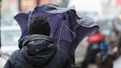 Eine Frau schützt sich mit einem Regenschirm vor Regen und Wind | Bild: picture-alliance/dpa